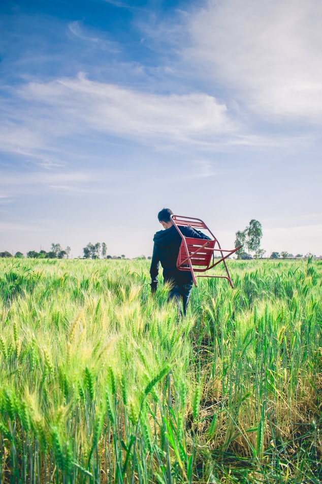man in black sweater carrying chair in middle of field man in black sweater carrying chair in middle of field