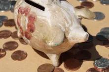 Vintage 1960s potter piggy bank from South America with scattered American coins on a brown background.