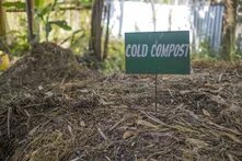 Photo: A sign reading "COLD COMPOST" stands on a mound of composting material in a garden.