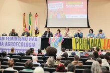 Photo: A discussion during an event on agroecology and public policies. People are seated at a table with banners in the background.