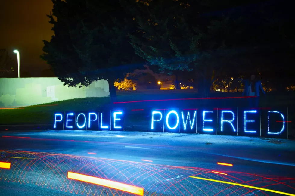 People powered message formed with neon letters on the side of  the road