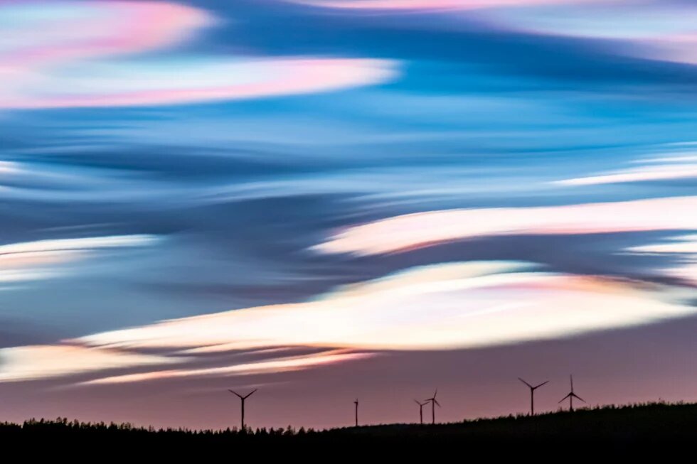 Wind turbines on a mountain top under a violet-blue sky