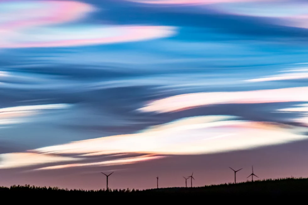 Wind turbines on a mountain top under a violet-blue sky