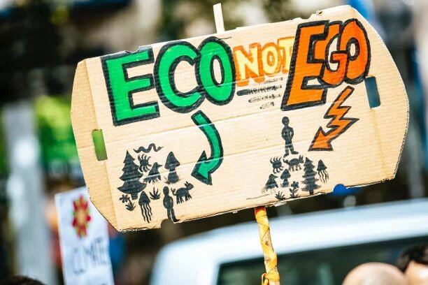 Person holding eco-not-ego sign 