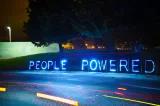 People powered message formed with neon letters on the side of the road